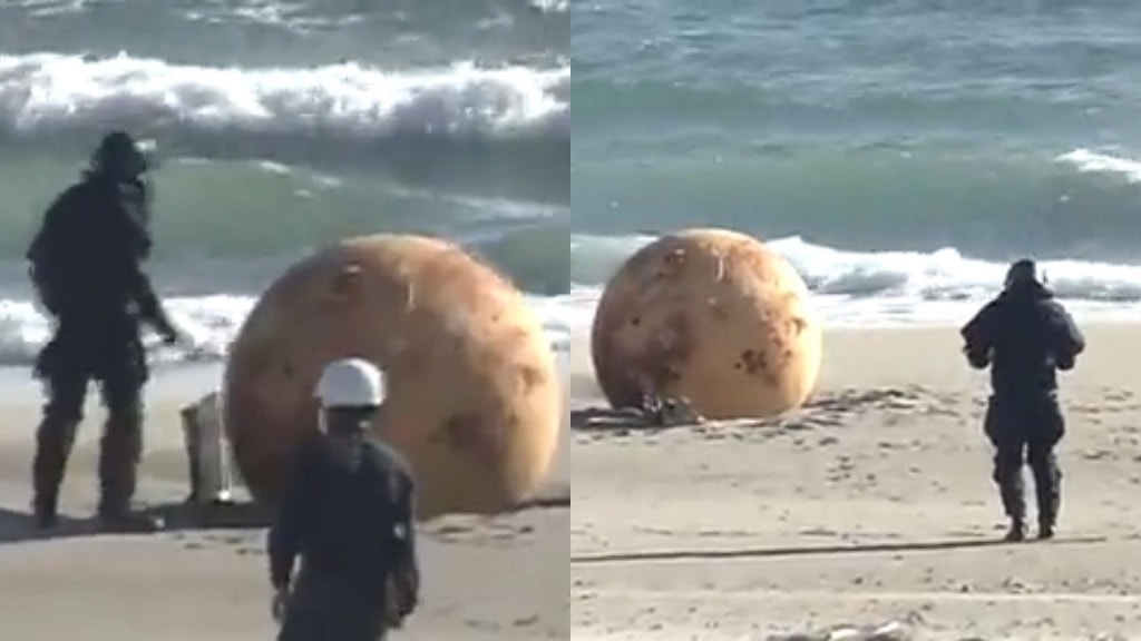 A bomb disposal squad inspects the mysterious ball that washed up on shore in Hamamatsu City
