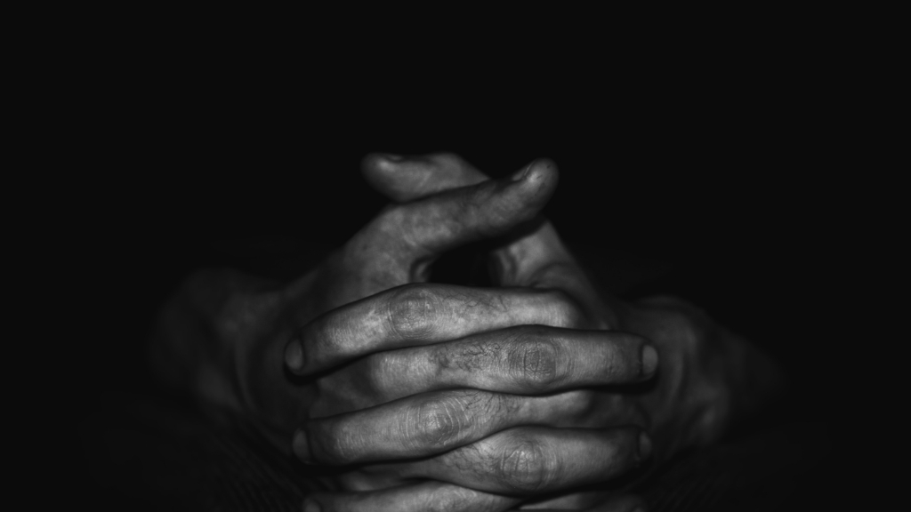 Greyscale photo of hands with fingers interlocked