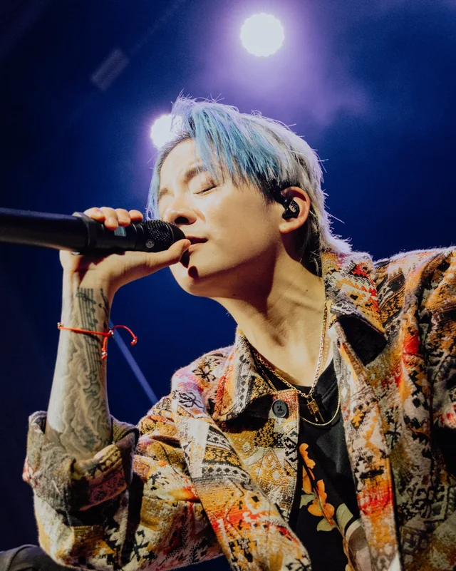 Amber Liu performing with a microphone under blue stage lighting
