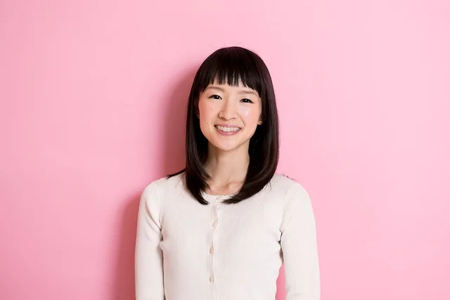 Marie Kondo seated against a pink background
